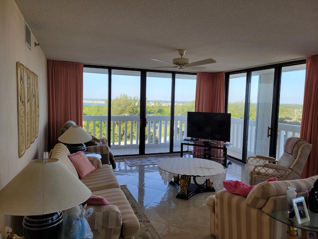 tiled living room with a textured ceiling, a wall of windows, and a ceiling fan