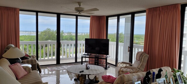 tiled living room with a textured ceiling, a healthy amount of sunlight, ceiling fan, and floor to ceiling windows