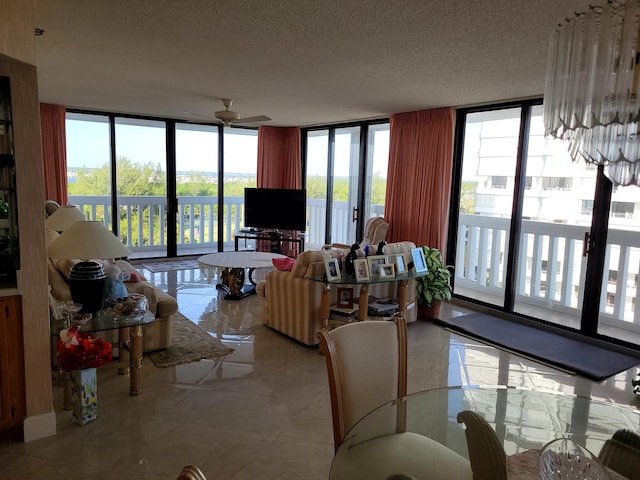 living room with a textured ceiling, ceiling fan, and floor to ceiling windows