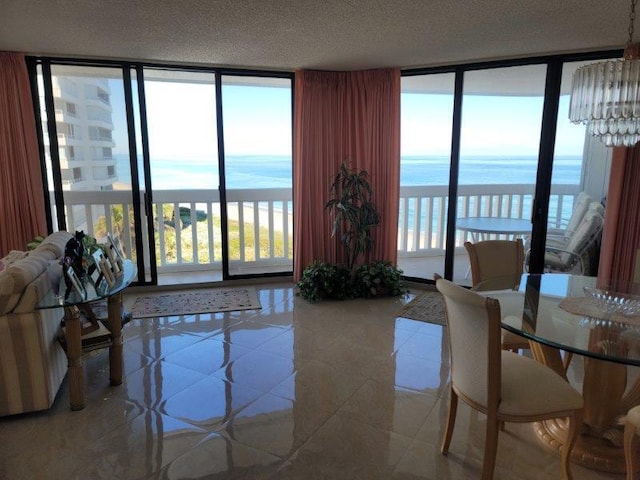 tiled living room with expansive windows, a water view, plenty of natural light, and a textured ceiling