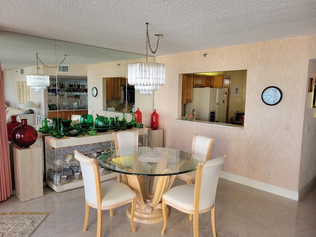 dining area featuring a chandelier, wallpapered walls, a textured ceiling, and baseboards