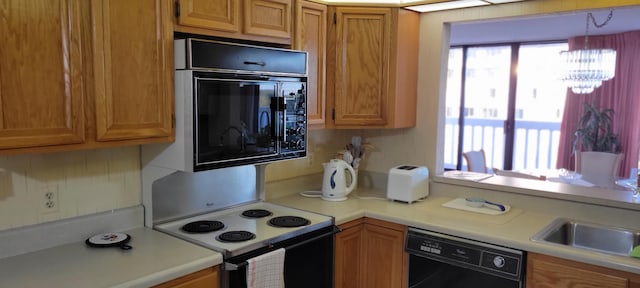 kitchen with decorative backsplash, pendant lighting, black appliances, and an inviting chandelier