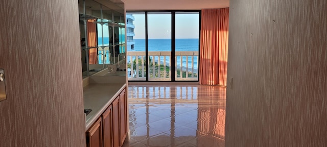 interior space featuring tile patterned floors, a water view, and floor to ceiling windows