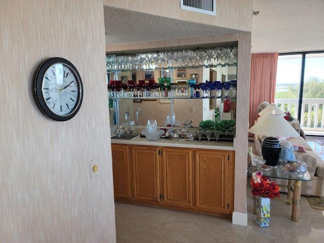 bar featuring light tile patterned floors, indoor wet bar, and a textured ceiling