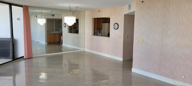 unfurnished room featuring visible vents, baseboards, a chandelier, marble finish floor, and a textured ceiling