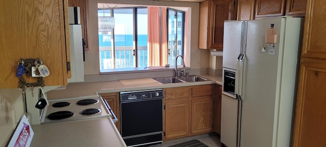 kitchen with a sink, white appliances, brown cabinetry, and light countertops