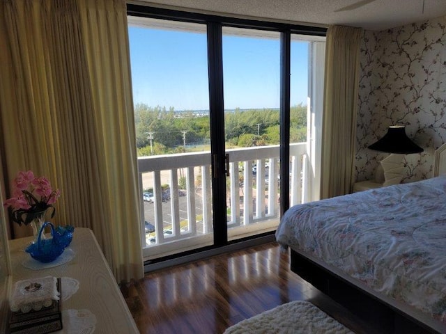 bedroom with wallpapered walls and wood finished floors