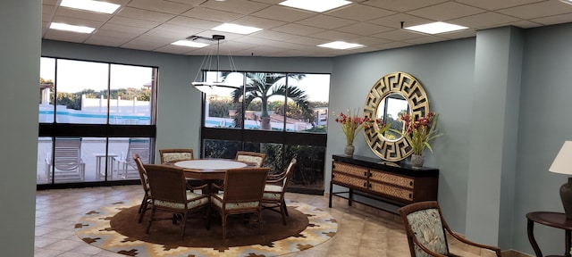 tiled dining area featuring a drop ceiling and a chandelier