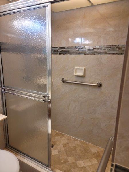 bathroom with a shower with door and toilet