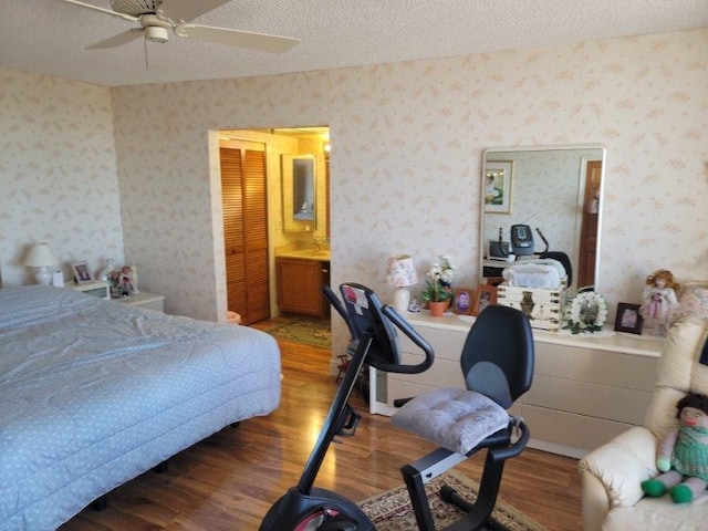 bedroom featuring wood-type flooring, a textured ceiling, ensuite bath, and ceiling fan