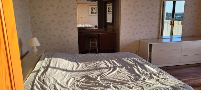 bedroom with wallpapered walls and wood finished floors