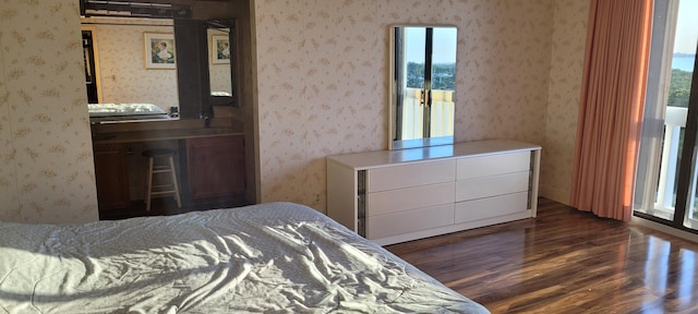 bedroom with dark wood finished floors and wallpapered walls