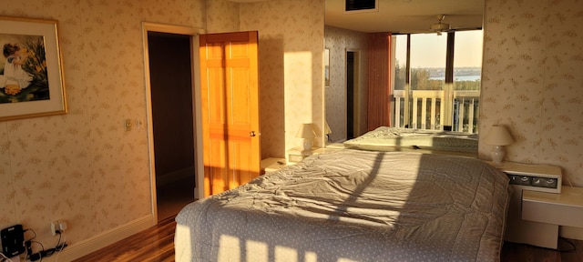 bedroom with wallpapered walls, access to exterior, wood finished floors, and baseboards