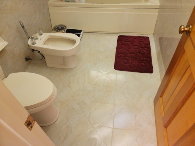 full bathroom featuring tile patterned floors, toilet, a bidet, and a tub