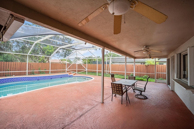 view of swimming pool featuring glass enclosure, ceiling fan, and a patio