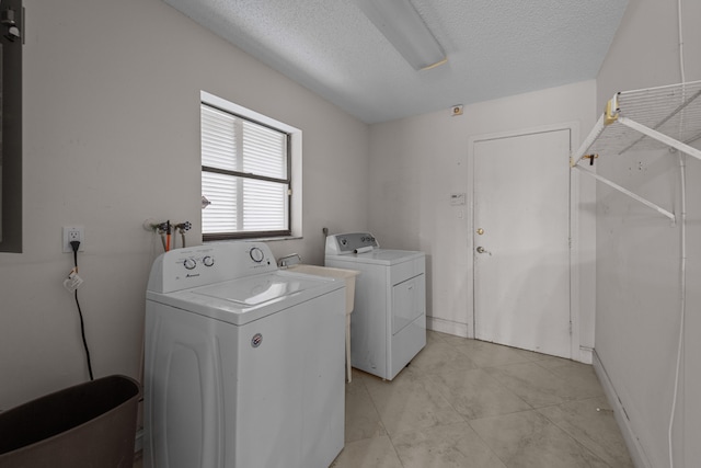 clothes washing area with washer and dryer and a textured ceiling