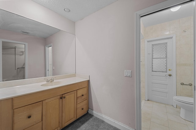 bathroom featuring tile patterned flooring, vanity, toilet, and a textured ceiling