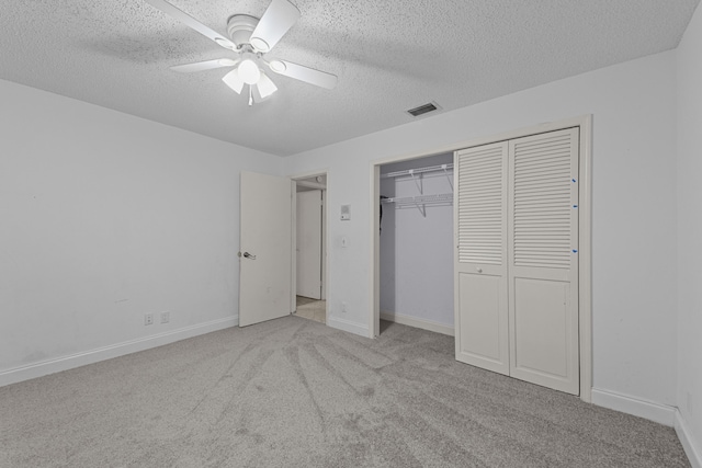 unfurnished bedroom with ceiling fan, light colored carpet, a textured ceiling, and a closet