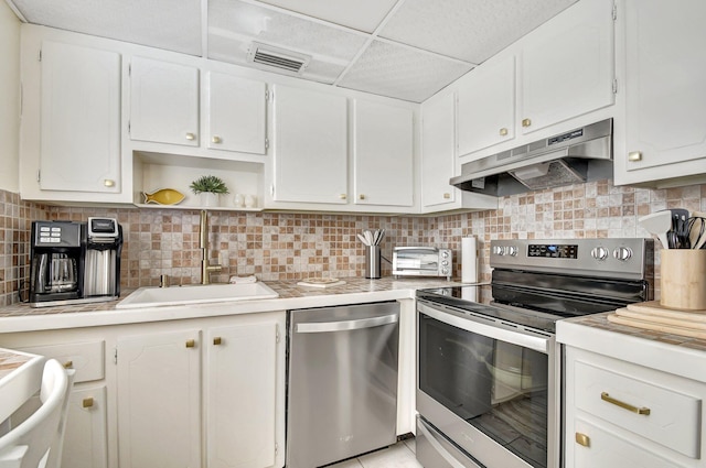 kitchen featuring a paneled ceiling, white cabinets, sink, appliances with stainless steel finishes, and tasteful backsplash