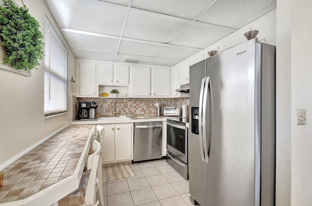 kitchen with white cabinets, appliances with stainless steel finishes, tasteful backsplash, and light tile patterned floors