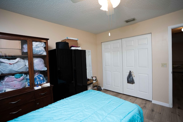 bedroom featuring ceiling fan, a closet, light hardwood / wood-style floors, and a textured ceiling