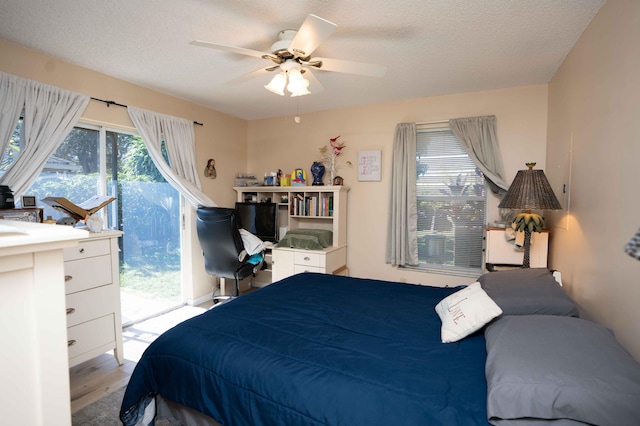 bedroom featuring ceiling fan, a textured ceiling, access to outside, and light hardwood / wood-style flooring