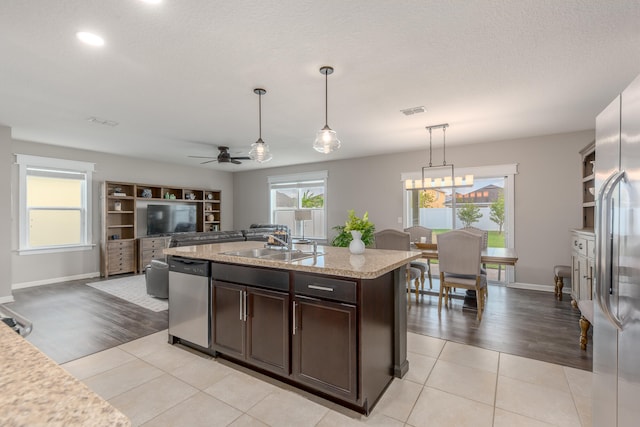 kitchen with dark brown cabinets, light wood-type flooring, stainless steel appliances, and pendant lighting