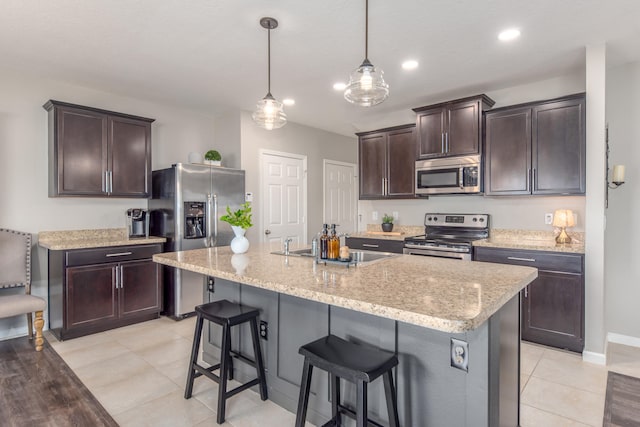 kitchen featuring pendant lighting, dark brown cabinetry, stainless steel appliances, and a center island with sink