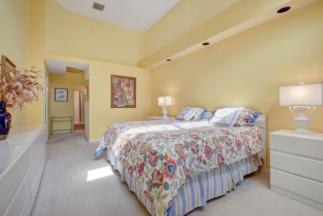 bedroom featuring light colored carpet, baseboards, visible vents, and a high ceiling