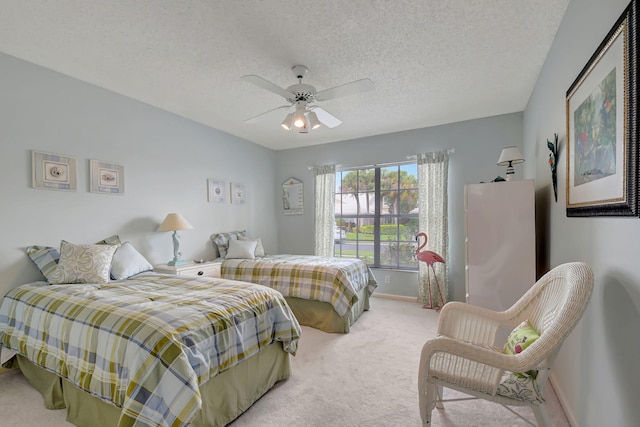 bedroom with ceiling fan, baseboards, a textured ceiling, and light colored carpet