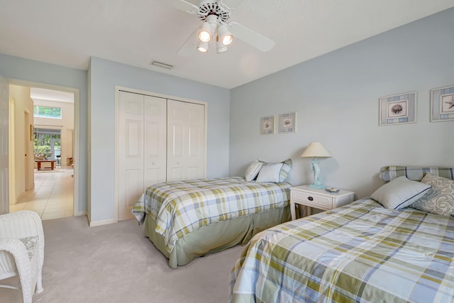 bedroom featuring ceiling fan, a closet, and light colored carpet