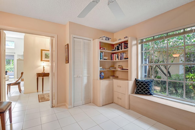 interior space with ceiling fan, a textured ceiling, and light tile patterned flooring