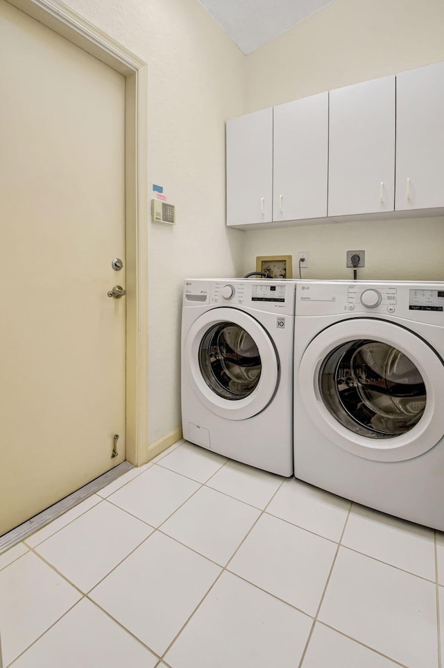 washroom featuring washer and dryer, cabinet space, and light tile patterned floors