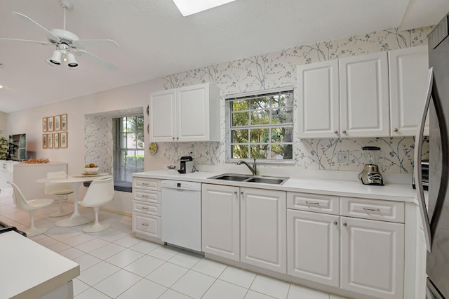 kitchen with light countertops, white cabinetry, white dishwasher, a sink, and wallpapered walls