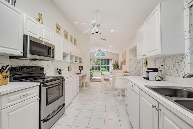 kitchen featuring stainless steel appliances, white cabinets, vaulted ceiling, and a sink