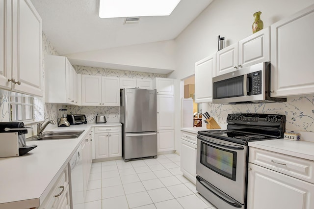 kitchen featuring lofted ceiling, a sink, white cabinetry, light countertops, and appliances with stainless steel finishes