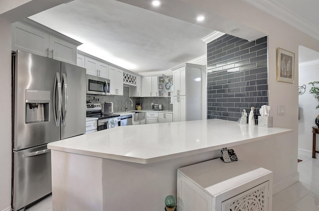 kitchen featuring kitchen peninsula, crown molding, decorative backsplash, white cabinets, and appliances with stainless steel finishes