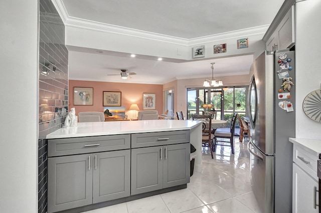 kitchen featuring gray cabinetry, ceiling fan with notable chandelier, light tile patterned flooring, kitchen peninsula, and stainless steel refrigerator