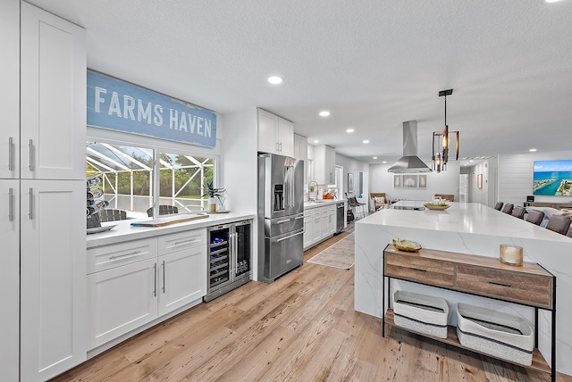 kitchen with stainless steel appliances, wine cooler, island exhaust hood, a textured ceiling, and white cabinets