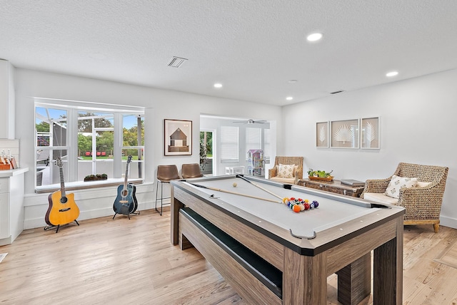 playroom featuring a wealth of natural light, a textured ceiling, and light wood-type flooring