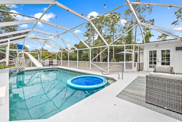 view of pool featuring french doors, a patio, glass enclosure, and a water slide