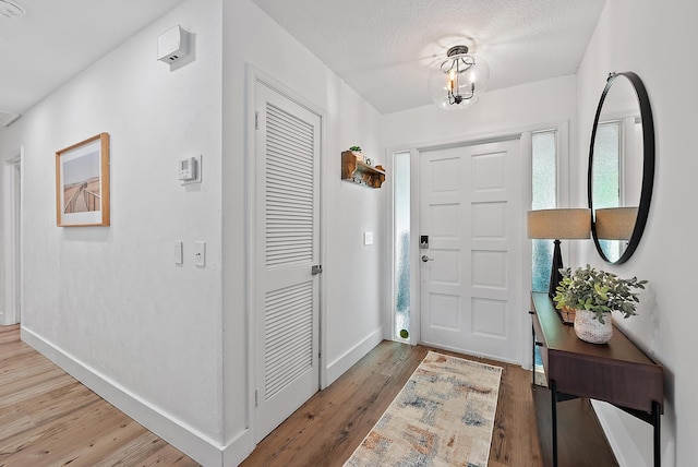 foyer entrance with hardwood / wood-style floors, a textured ceiling, and a chandelier