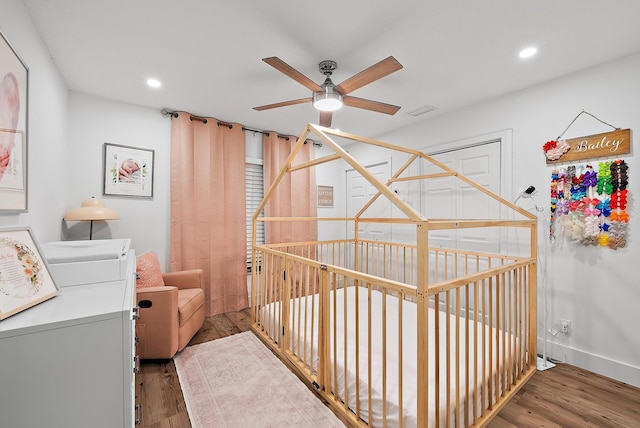 interior space featuring hardwood / wood-style flooring, ceiling fan, a crib, and washer / clothes dryer