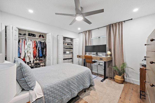 bedroom featuring ceiling fan, light hardwood / wood-style floors, and multiple closets