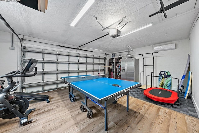 rec room with wood-type flooring, a textured ceiling, and a wall mounted AC