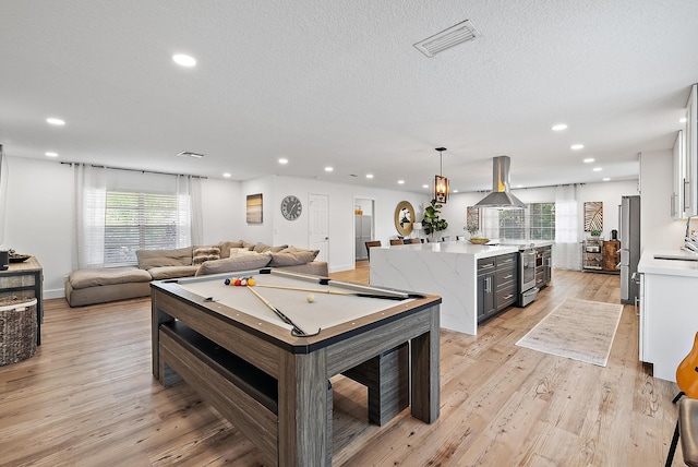 playroom featuring plenty of natural light, a textured ceiling, billiards, and light hardwood / wood-style flooring