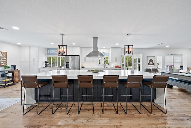 kitchen with a large island, a kitchen breakfast bar, white cabinetry, and stainless steel fridge with ice dispenser