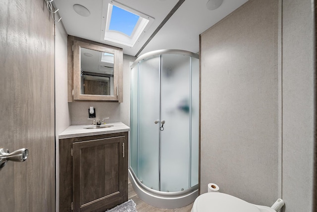 bathroom featuring vanity, a skylight, hardwood / wood-style flooring, toilet, and a shower with shower door