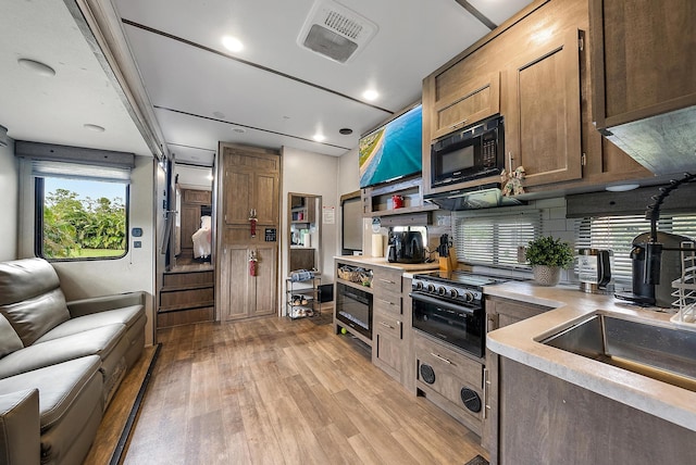 kitchen with sink, light wood-type flooring, and black appliances