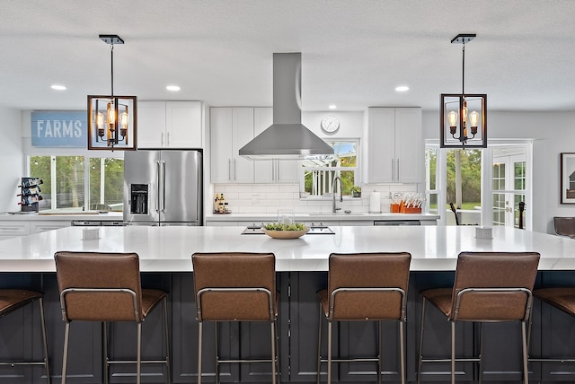 kitchen with stainless steel refrigerator with ice dispenser, island exhaust hood, plenty of natural light, a spacious island, and white cabinets